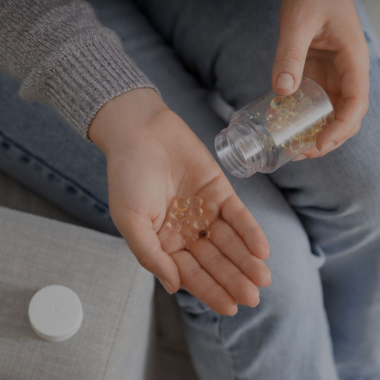Person holding pills in their hand with a bottle of pills nearby.