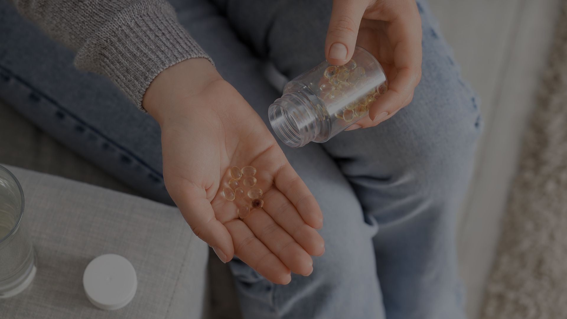 Person holding pills in their hand with a bottle of pills nearby.